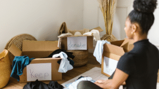 “keep”“donate”“trash”のラベルが貼られた箱と、それを見つめる女性。モノの行き先に悩む姿。
