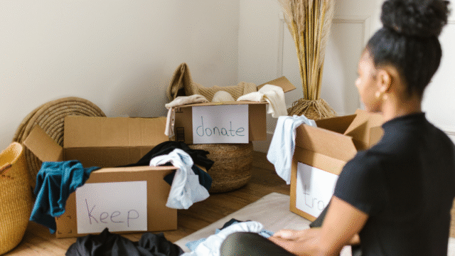 “keep”“donate”“trash”のラベルが貼られた箱と、それを見つめる女性。モノの行き先に悩む姿。