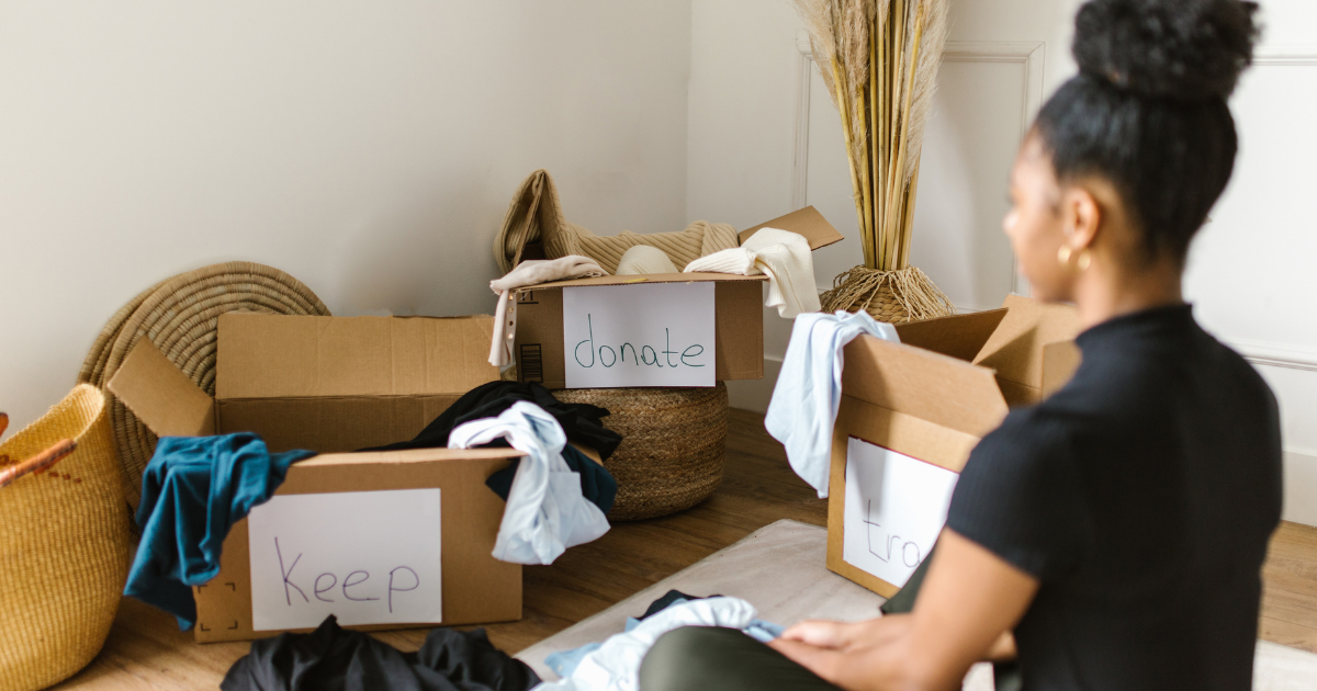 “keep”“donate”“trash”のラベルが貼られた箱と、それを見つめる女性。モノの行き先に悩む姿。