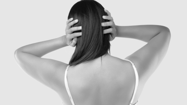 頭を抱え込む女性の後ろ姿。捨てられない葛藤や気持ちの整理の難しさを象徴。