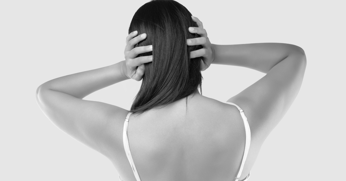 頭を抱え込む女性の後ろ姿。捨てられない葛藤や気持ちの整理の難しさを象徴。