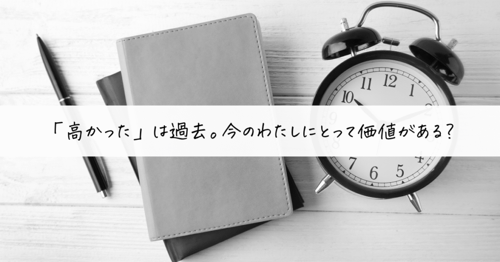 黒の目覚まし時計と手帳、ボールペンが並ぶモノクロ写真。“『高かった』は過去。今のわたしにとって価値がある？”という言葉が中央に書かれている